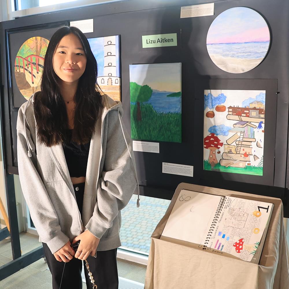 Lizu stands in front of her artwork