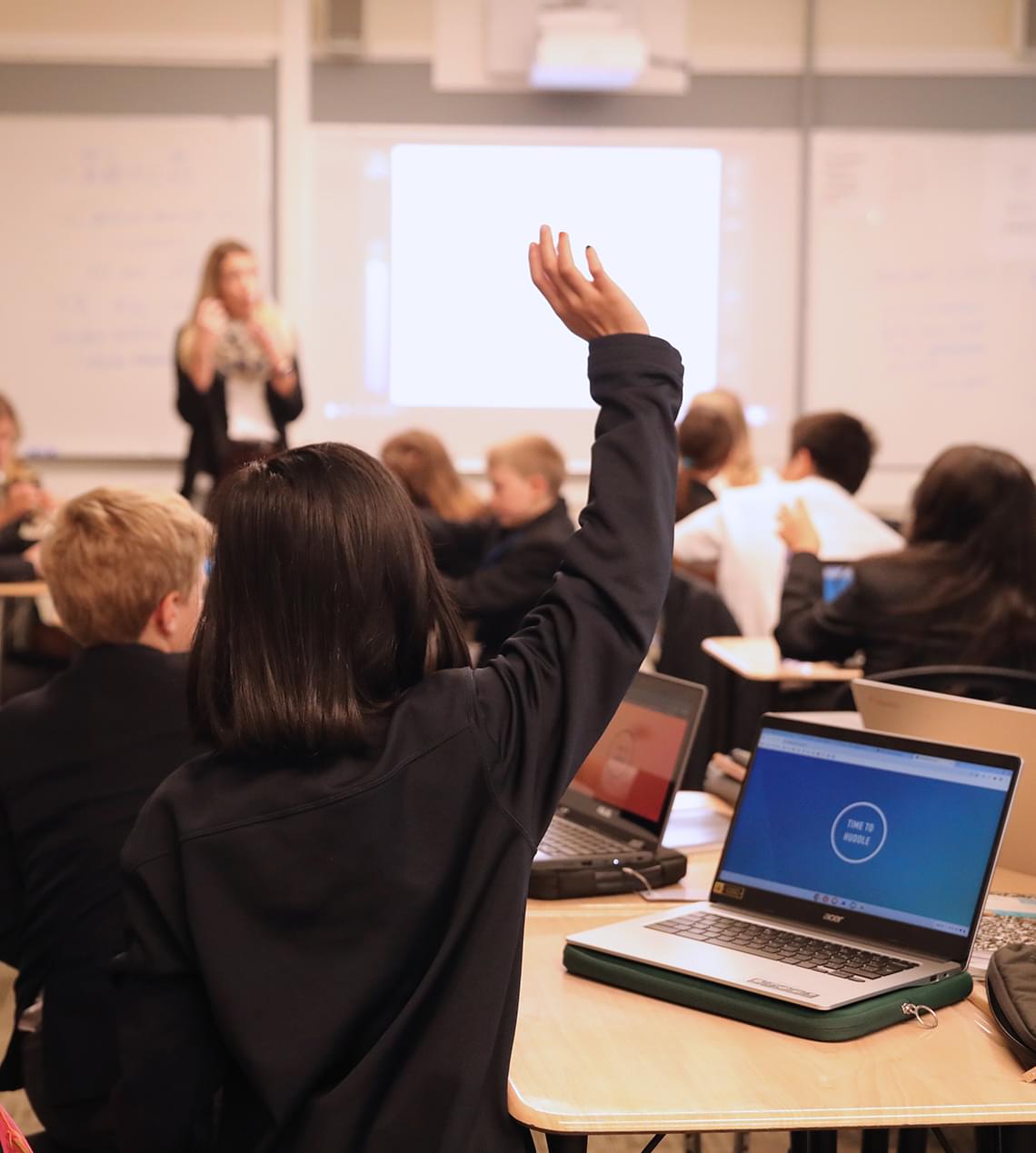 student with hand up in classroom