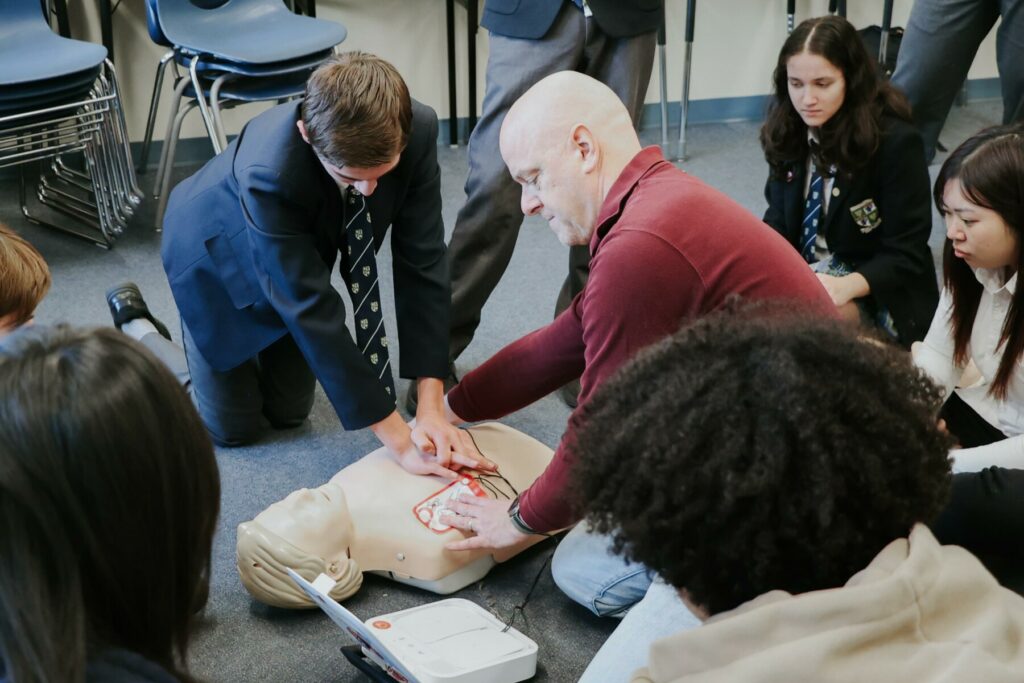 students learning CPR and AED training with the support of a parent volunteer