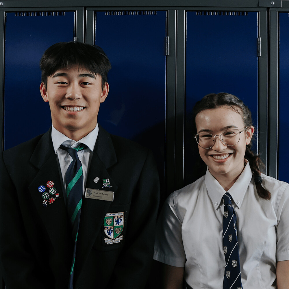 Grade 12 students smiling in front of lockers