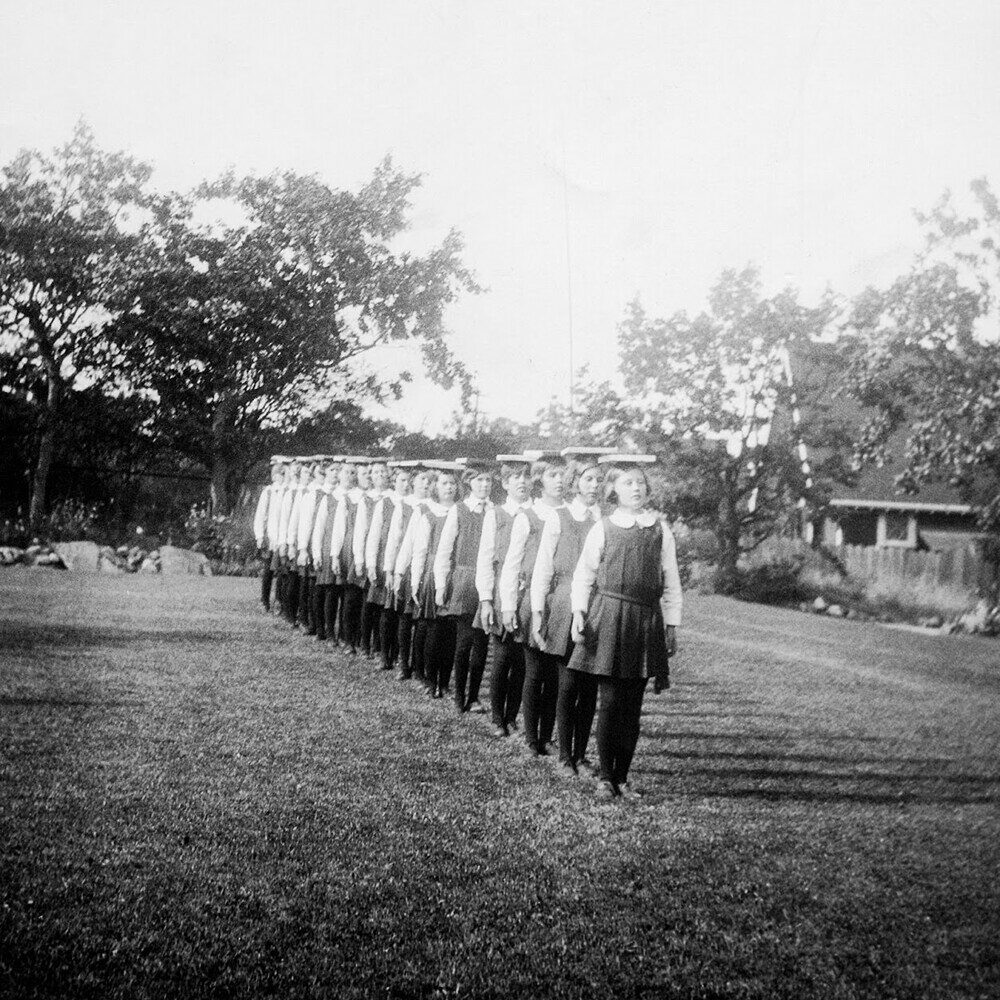 archival photo featuring students balancing books on head