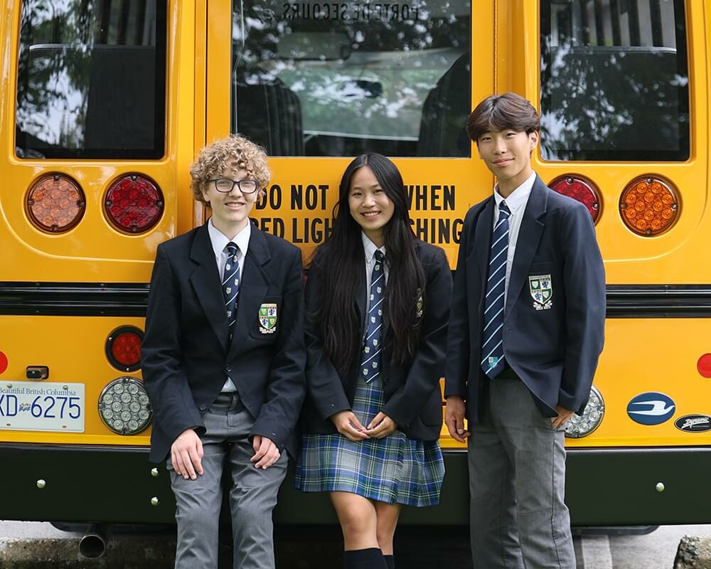 Three students standing from of the Westshore Express school bus