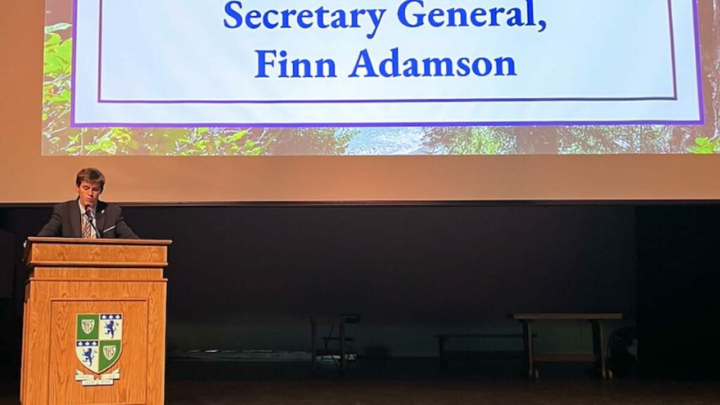 Student speaker at a podium addressing delegates during the opening ceremony of GMUN 2025