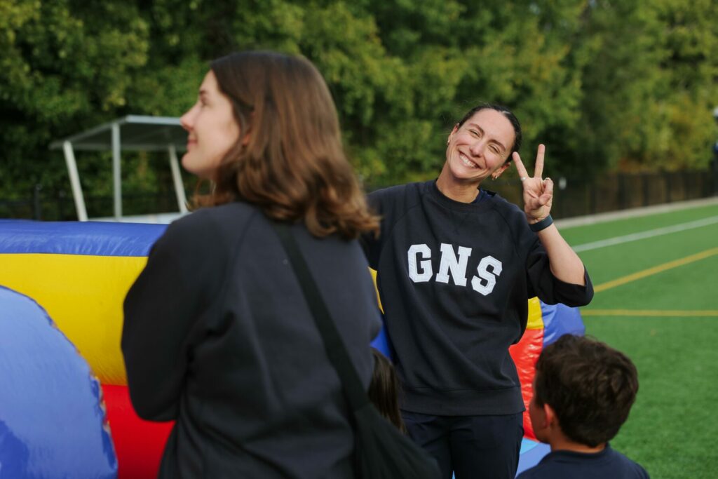 GNS teacher smiles and makes a peace sign while supervising students at the Family Carnival.