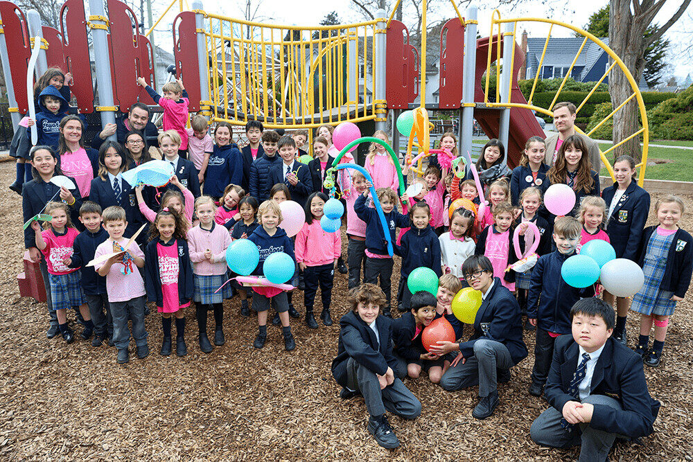 Students pose together outdoors after a design challenge workshop, with colourful balloons and creations.