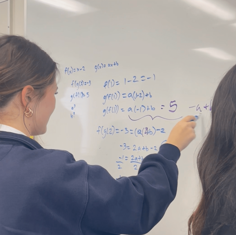 students working on an assignment on a whiteboard