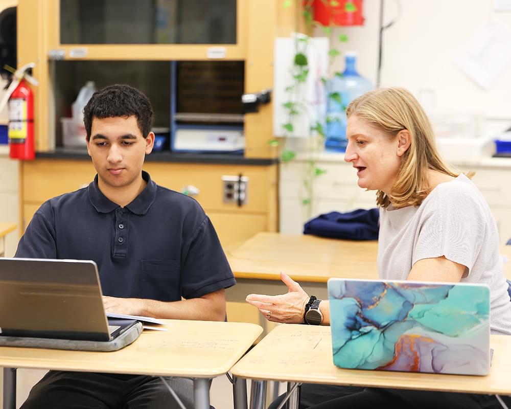 A Senior School student helping a student with IB Biology